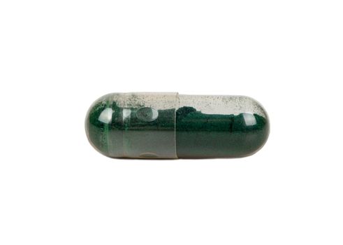 Transparent capsule with medicinal green grass isolated on a white background