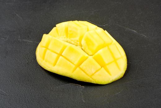 Juicy half of a ripe mango on a dark concrete background
