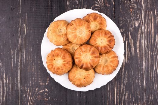 Homemade fresh baked biscuits on a white plate on a dark wooden table top view