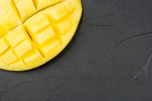 Part of a sliced mango half on an empty dark background
