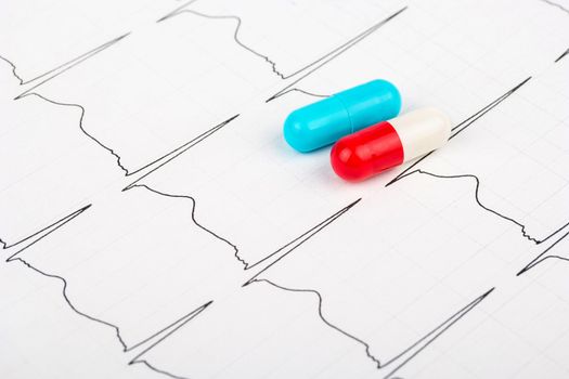 Cardiogram with the rhythm of the heartbeat, and two multi-colored capsules