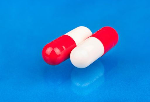 Red white capsules from a headache close up on a blue background