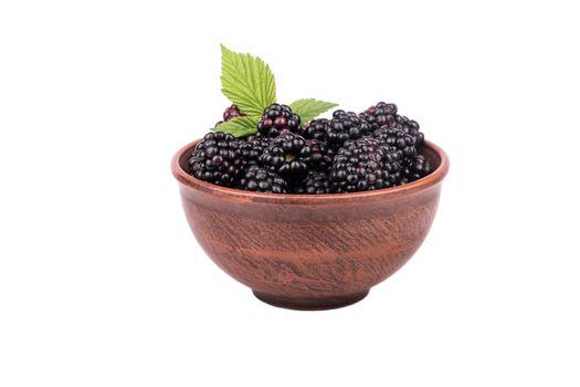 Full bowl of fresh blackberries with leaves isolated on a white background