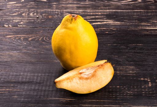 Ripe quince with a slice on a wooden background