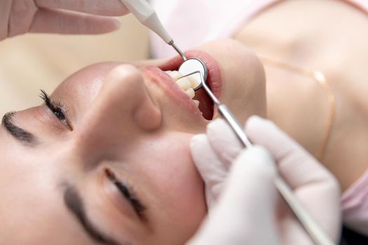 Dentist examining patient teeth with mirror in dentist clinic. Having dental checkup