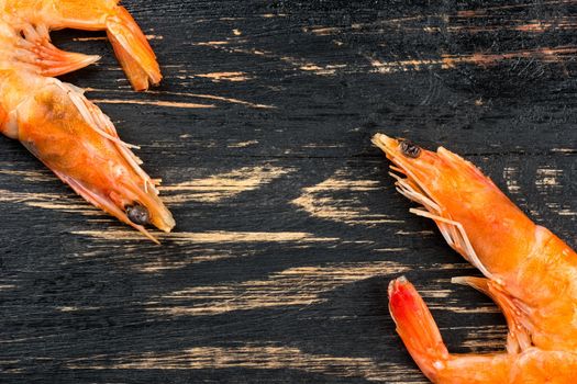 Two boiled shrimp on a wooden table, top view