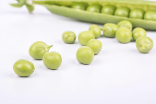 Grains green peas scattered from the pod on a white background