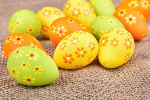 Scattered colored easter eggs with flowers on sackcloth