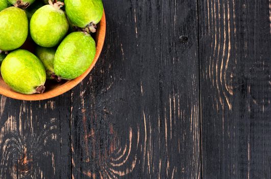 Part of bowl full of fresh fruit Feijoa on a blank wooden background top view