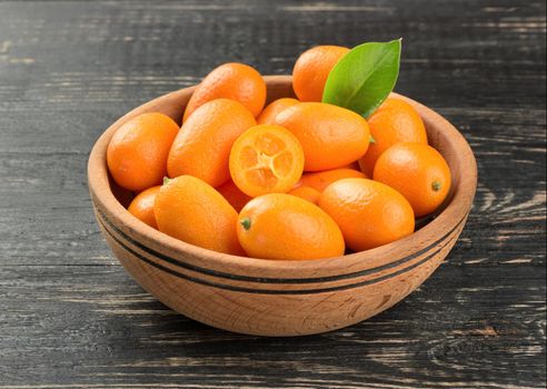 Bowl full of fresh fruit kumquat on a dark table