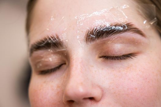 Caucasian woman on the procedure of permanent styling and coloring of eyebrows