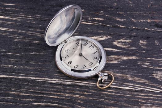 Opened old pocket watch on a dark wooden background