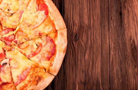 Part fresh pizza with sausage on a wooden background top view