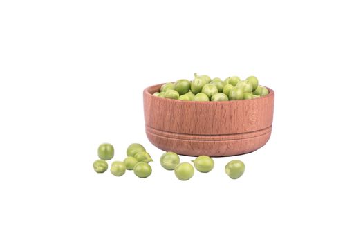 Fresh green peas in a wooden bowl and scattered grain on a white background