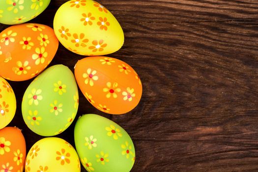 Multi-colored Easter eggs with flower pattern on wooden background a top view