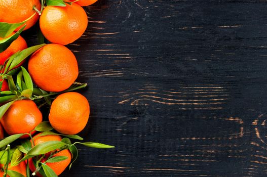 Lots of fresh tangerine with leaves on a dark wooden background a blank