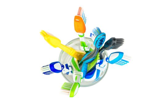 Many toothbrushes in a glass on a white background, top view