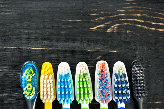 Multicolored toothbrushes on a wooden background close up