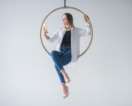 Caucasian woman gymnast on an aerial hoop takes a selfie on a smartphone