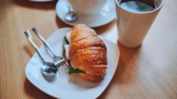 Croissant and meat on a girl's table at lunchtime