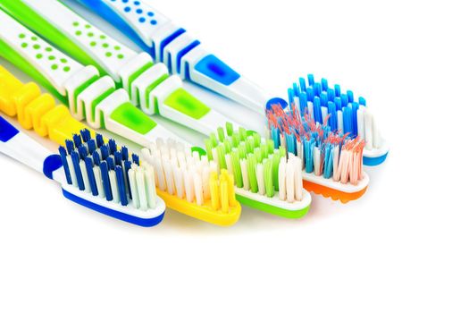 Several multi-colored toothbrushes on a white background closeup
