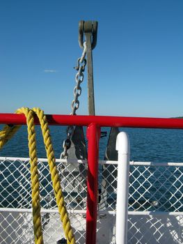 Looking off the front of a ferry boat with an anchor, fence and rope in the foreground.  A journey on a ferry boat to Casco island off the coast of Portland maine.