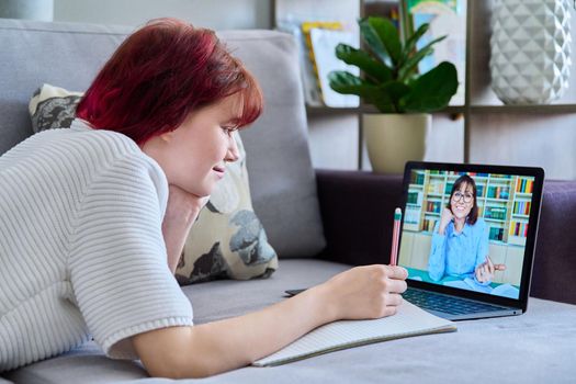 Teenage female student at home looking listening online lesson webinar teacher on laptop screen. Virtual communication, video call chat conference. E-education technology adolescence distance learning