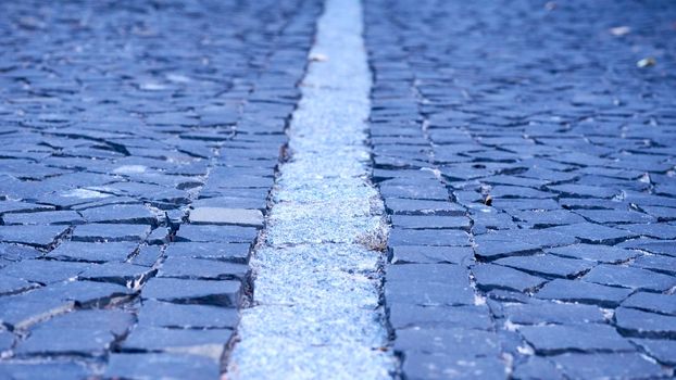 of a piece of ground, covered with concrete, asphalt, stones, or bricks.Paving stones. Cobblestone pavement divided by a granite strip close-up.