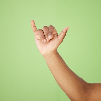 Cropped shot of a man showing a hand sign against a green background.