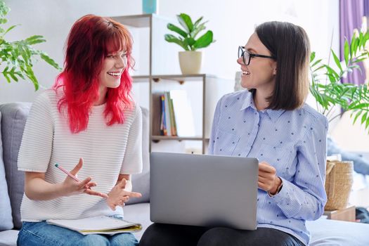 Female teacher teaches student teenage girl, sitting together on couch in office, educational counseling, using laptop. Education, knowledge, individual training, adolescence concept