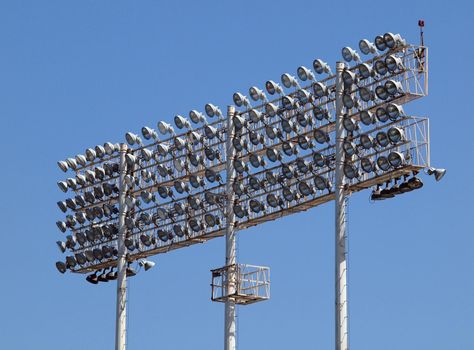 Stadium-style lights, taken at Oakland Colisuem looking forward, clear blue sky background, during the daytime so the lights are off.