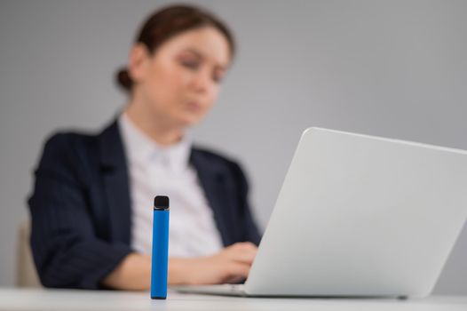 Business woman smoking a disposable vape while sitting at her desk