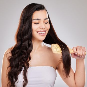 Studio shot of a young woman brushing her hair.