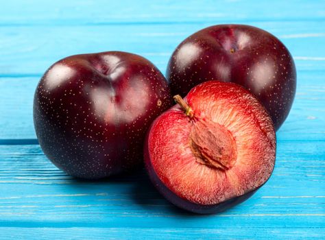 Fresh large red plum with a mate on wooden background