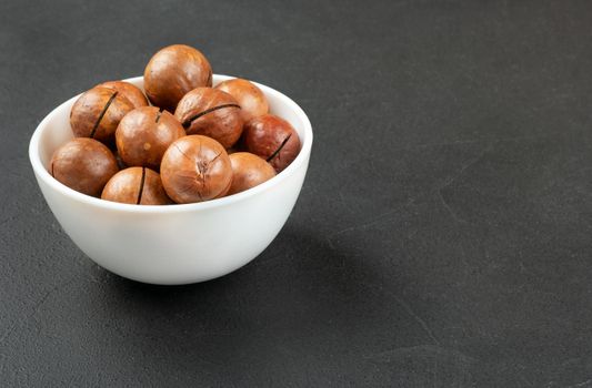 Macadamia nuts in a white bowl on a dark background