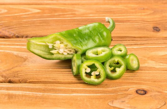 Half fresh green pepper slices on a wooden background