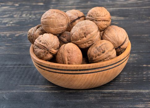 Walnut in shell in a bowl on wooden background