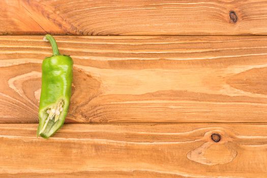 Half of green chili on a blank wooden background, top view