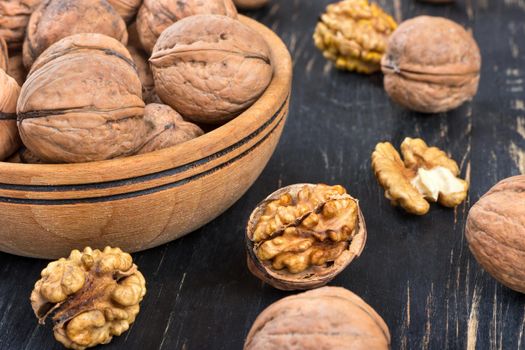 Walnuts in a bowl and scattered on wooden background