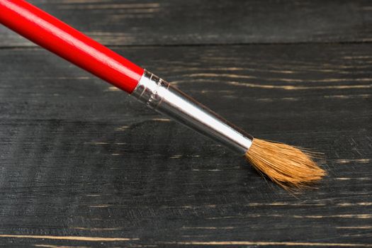 Red brush to draw on the dark table closeup