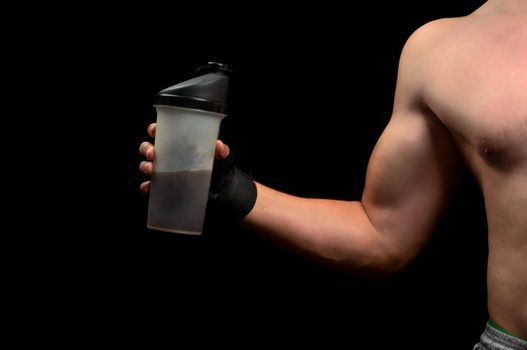Beginner bodybuilder is holding a sports nutrition on a black background
