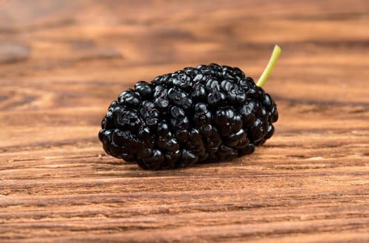 Fresh black mulberries on a wooden background closeup