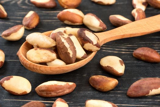 Scattered Brazil nuts in spoon on table, close up