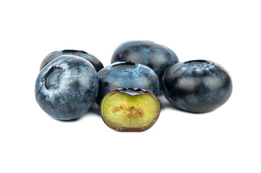 Small bunch of fresh blueberries with a half on a white background