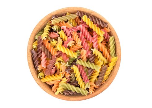 Colored pasta fusilli in a wooden bowl on white background, top view