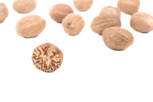 Half nutmeg with scatter nuts on a white background