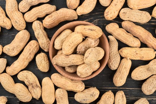 Peanuts in shell and scattered on a wooden background, top view