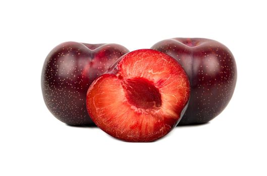 Big red plum with juicy half on white background