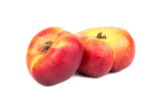 Two fresh flat peaches on a white background