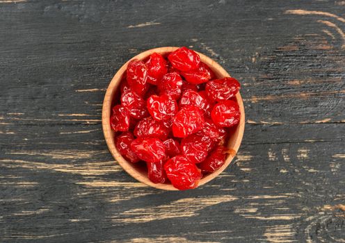 Small bowl with dried cherries on a dark table, top view